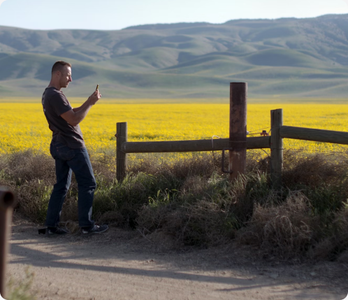 Person in a field taking a photo with a smartphone